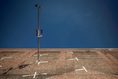 The frog-eye view transforms a paved parking lot in Cologne into a steep wall against a deep blue