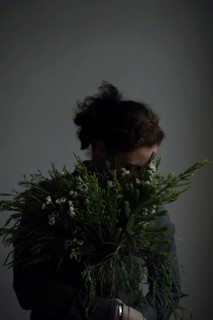 Woman holding ostrich with grasses, face covered