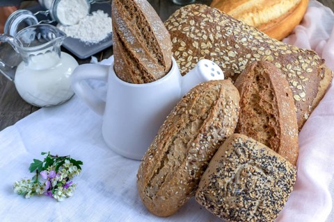 Freshly baked artisanal bread assortment, including baguettes, rolls, and loaves, with flour and