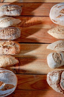 Various types of fresh artisanal bread, including baguettes and round loaves, arranged on a rustic