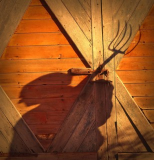 Farmer with a pitchfork against a barn door in Vermont, USA