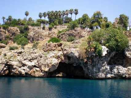 A panoramic view of a grotto with caves in the mountain cliffs jutting out from the azure and