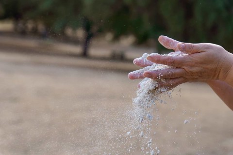 Hands pouring white sand, symbolizing the passage of time, impermanence, and the fleeting moments