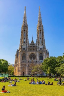 Young people enjoy the spring sun on the meadow in front of the neo-gothic votive church, Vienna,