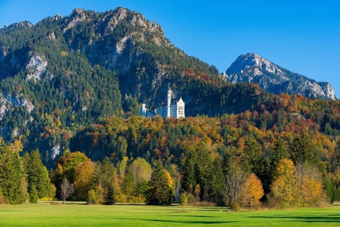 Neuschwanstein Castle is idyllically situated at the foot of mountain peaks in the midst of an
