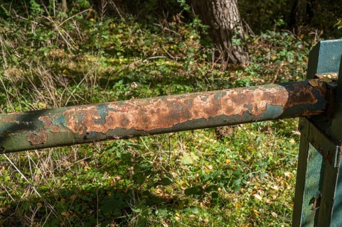 Borken, NRW, Germany, Rust and peeling paint corroding a green metal barrier in a forest setting