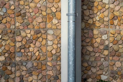 Borken, NRW, Germany, RPebble stone wall with a vertical metal drainpipe creating an interesting