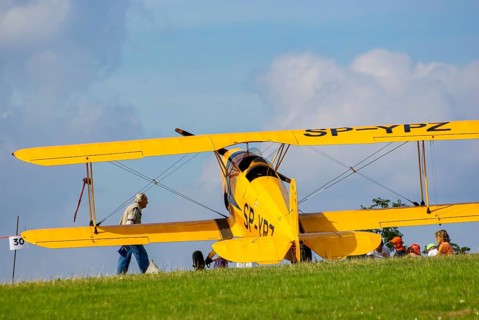 A Bücker Bü 131 Jungmann biplane parked at the edge of the airfield, SP-YPZ registration, as part