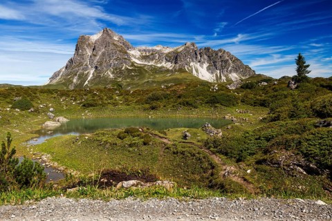 A small lake nestled in an alpine landscape with the distinctive Großer Widderstein mountain,