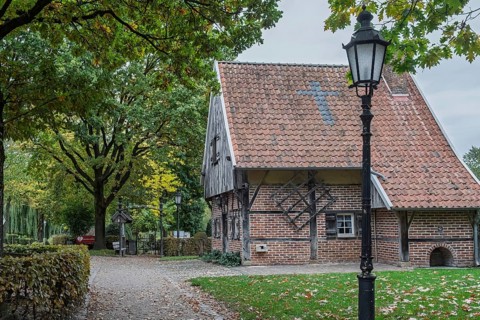 Quiet village scene with half-timbered house and lantern under old trees, a path leads through