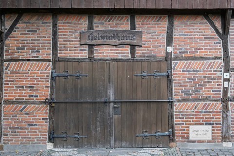 Wooden and brick gate of a medieval half-timbered house with rustic sign, Münsterland, North