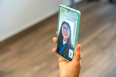 Person holding a smartphone, engaging in a virtual medical consultation with a doctor appearing on