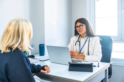 Female doctor in a white lab coat and stethoscope consulting a patient, providing professional