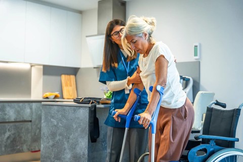 Young female caregiver is providing support and assistance to a senior woman, helping her during a