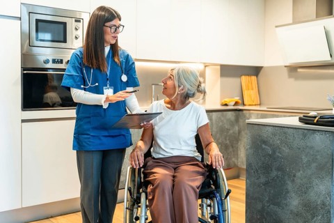 Professional nurse in uniform explaining medical information to an elderly woman sitting in a