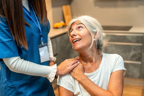 Caregiver gently supporting senior woman at home, offering compassionate medical assistance,