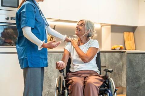 Nurse supporting an elderly woman in a wheelchair, providing care and medicine, symbolizing home