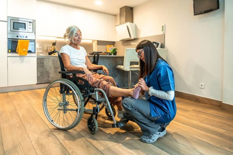 Physiotherapist in uniform giving gentle foot massage and rehabilitation treatment to a smiling