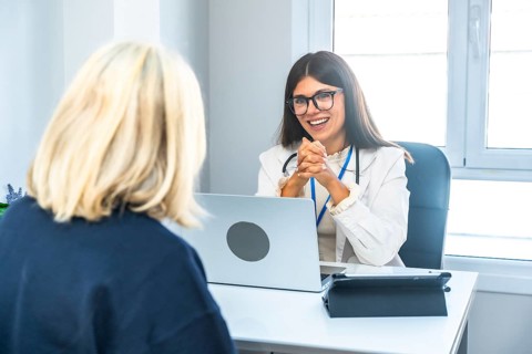 Young female doctor wearing a lab coat and stethoscope, smiling while actively listening to a