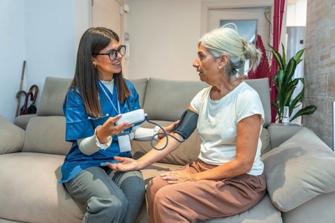 Healthcare professional checking blood pressure for an elderly woman in her home, providing
