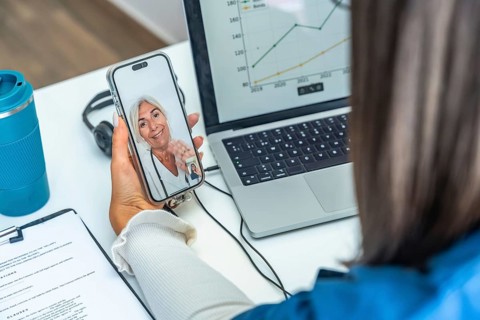 Woman having an online telemedicine consultation with a senior female doctor on a mobile phone,