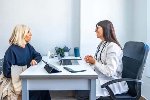 Doctor consulting with an older woman, having a medical appointment in a modern office, providing