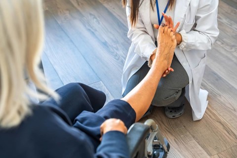 Medical professional in a white lab coat examining a senior patient's bare foot, providing care and