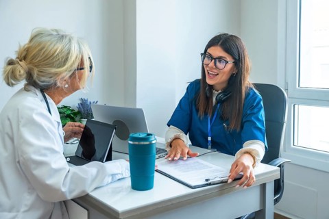Healthcare professionals, a doctor in a lab coat and a nurse in scrubs, sitting at a desk and