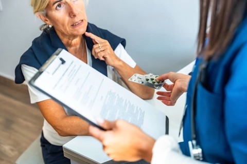Medical professional discussing treatment options and handing blister pack of pills to an elderly