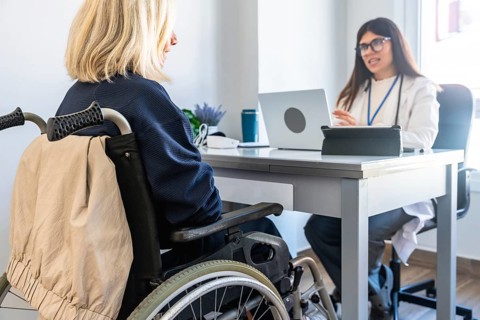 Patient in a wheelchair receiving medical advice from a female doctor during a healthcare