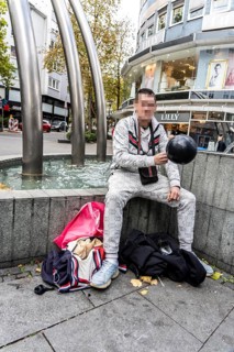 Man in public consumes laughing gas filled into a balloon with a gas cartridge, still legal
