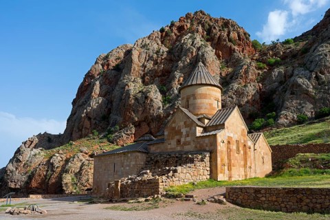 A stone church nestled in a rocky landscape with blue sky in the background, Noravank monastery,
