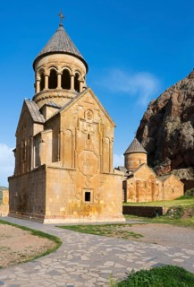 An ornate stone church with a paved path in the foreground and a blue sky ceiling, Noravank