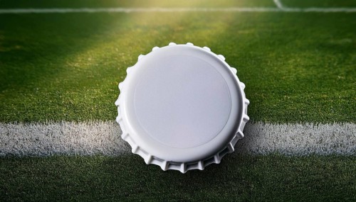 A white bottle cap placed on a soccer field's grass near a white line, symbolizing sports,