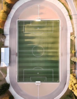 A soccer field with a white line in the middle. The field is surrounded by a track, AI generated