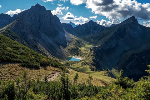 View from the Sallfelder Höhenweg hiking trail to Lache See and mountains of the Allgäu Alps, left