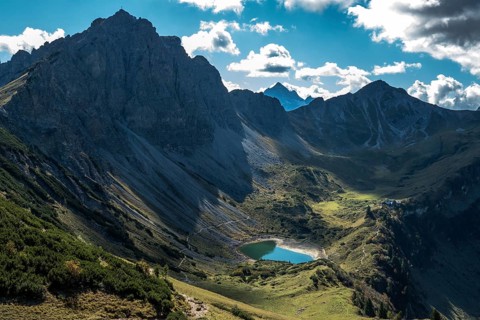 View from the Sallfelder Höhenweg hiking trail to Lache See and mountains of the Allgäu Alps, on