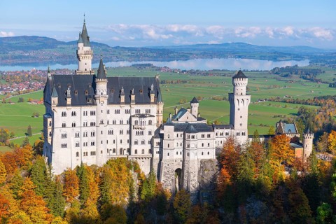 Impressive Neuschwanstein Castle stands majestically in an autumn-colored landscape with