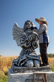 Chandler, Minnesota - Artist Primi Monteiga re-paints her concrete sculpture of an angel in the