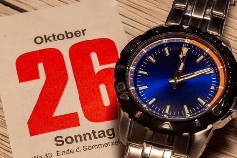 Wintertime 2025 time change: Close-up of a wristwatch and a sheet of a tear-off calendar showing