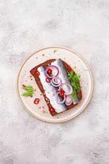 Sandwiches, Herring fish, on dark rye bread, sprinkled with onion, chili pepper and herbs, on a