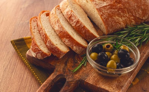 Sliced ciabatta, on a chopping board, with rosemary and olives, Italian bread, close-up, Italian