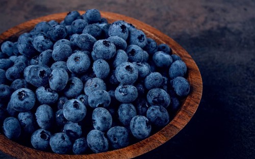 Fresh blueberries, in a wooden bowl, on the table, top view, close-up, no people