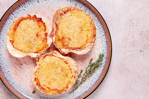Scallop, baked in shells, with cheese and spices, on a plate, homemade