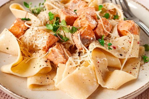 Tagliatelli pasta, with salmon slices and herbs, on a decorative plate, homemade, no people