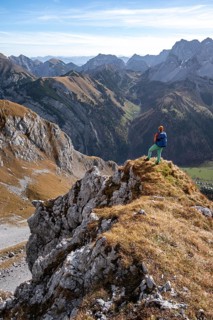 Hiker stands on a rock and looks into Ta, hiking to Gamsjoch, down the Ahornboden valley, eastern