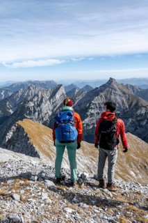 Two hikers on the summit of Gamsjoch look at the mountains, eastern Karwendel, Tyrol, Austria