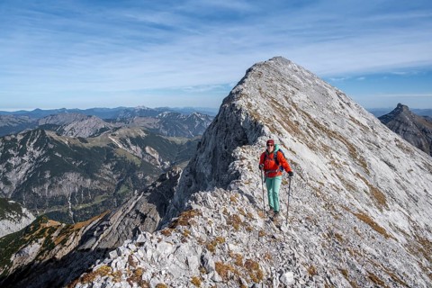 Female hiker on the summit ridge of the Gamsjoch, behind rock faces of the Laliderer Spitze,