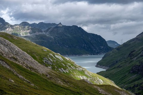 View of a lake in a valley surrounded by mountains, dramatic sky with low-hanging clouds, Lac des
