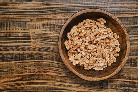 A wooden bowl with peeled walnuts, showcasing their rich texture and natural color on a rustic
